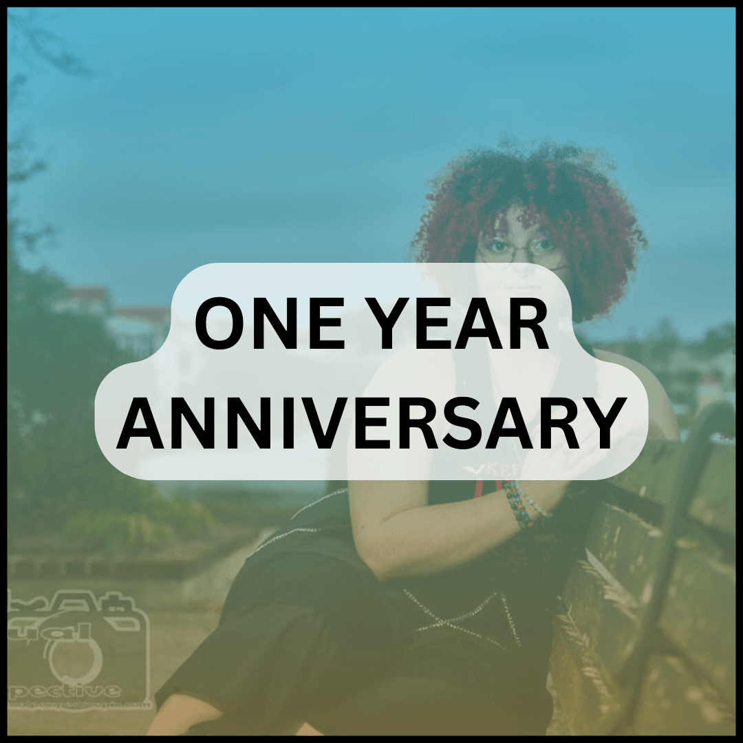 Curly haired female sitting on bench overlayed with a blue to orange gradient and the text ‘one year anniversary’
